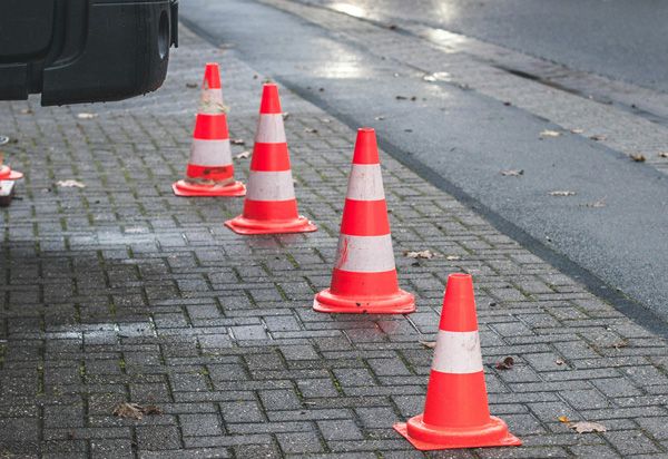 Rot-weiße Leitkegel auf dem Bürgersteig der Alleestraße in Bochum, die Zufahrt zum Kundenparkplatz im Hof bleibt frei