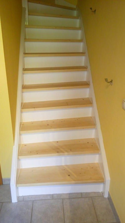 Holztreppe abgeschliffen und neu lackiert — die neu lackierte Treppe frontal vor der gelben Wand
