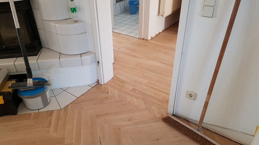 Eiche-Massivparkett im Fischgrätverband — Blick am gefliesten Ofensockel vorbei in den Nebenraum