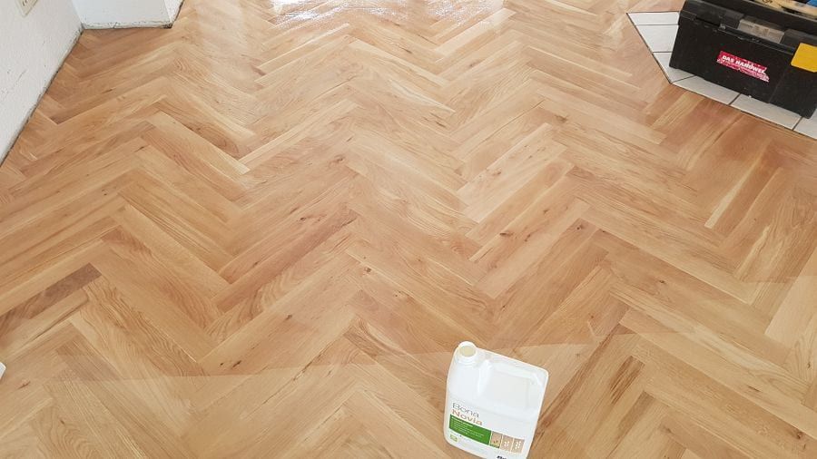 Eiche-Massivparkett im Fischgrätverband — flacher Blick über den Verband bis zur gefliesten Schwelle