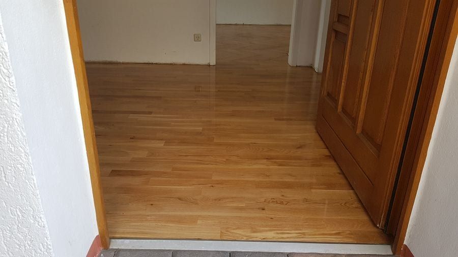 Eiche-Massivparkett im Fischgrätverband — Blick von der Wohnungstür über die Schwelle in den Flur