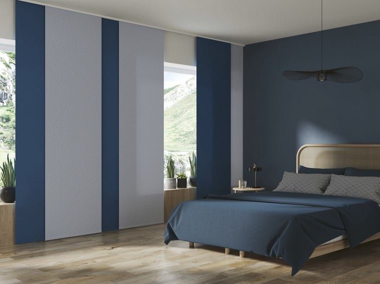 Flächenvorhang an großer Fensterfront — blau-weiße Bahnen neben dem Bett im Schlafzimmer