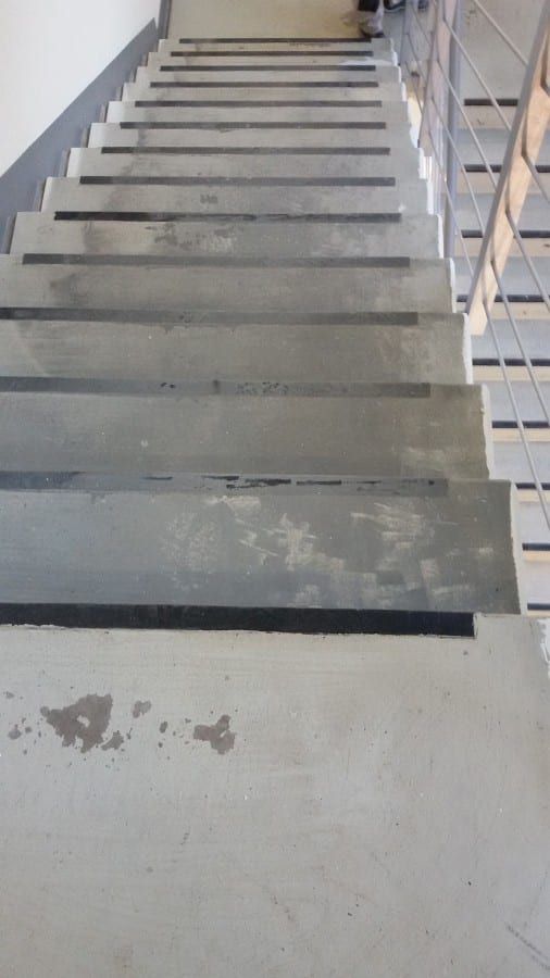 Fluchttreppenhaus mit Kautschukformtreppen — Blick von oben auf die rohen Stufen und das Betonpodest