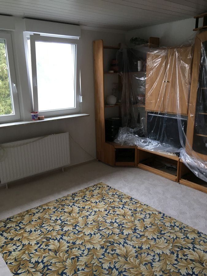 Teppichboden mit umlaufendem Fries — verlegte Fläche mit Blumenmuster, Möbel an der Wand abgedeckt