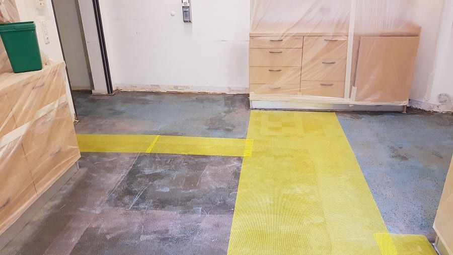 Neue Bodenbeschichtung, schichtweiser Aufbau — Restfläche des alten Belags im ausgeräumten Raum