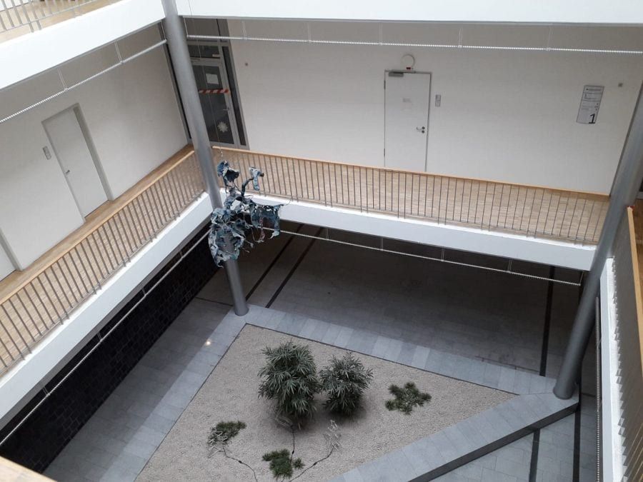 Eiche-Hochkantlamelle geschliffen und lackiert — Blick über das Geländer in den begrünten Innenhof