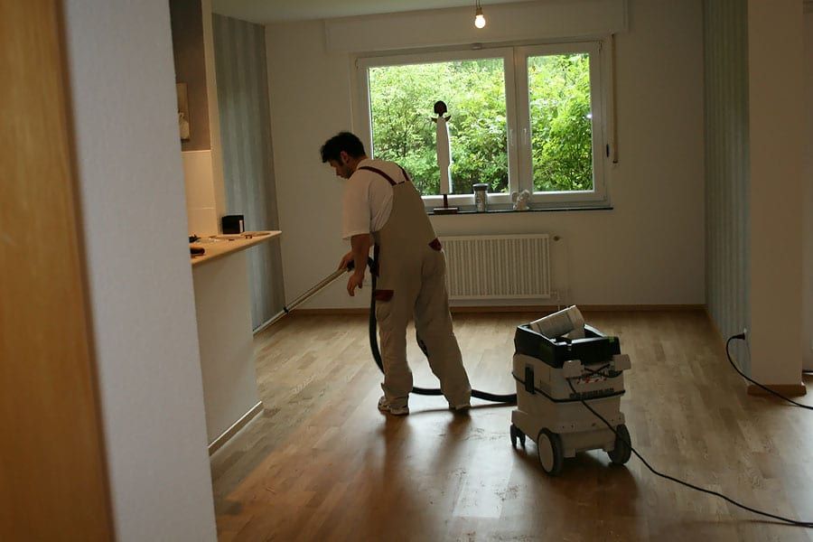 Wohnungsrenovierung mit Fertigparkett Eiche — Handwerker beim Absaugen im Raum mit der Küchenzeile