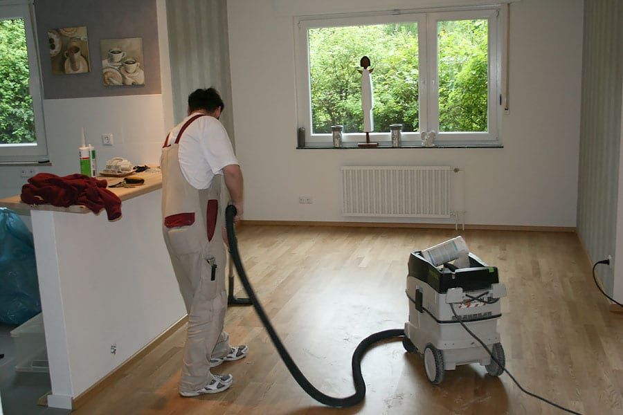 Wohnungsrenovierung mit Fertigparkett Eiche — Handwerker mit Saugschlauch am Küchentresen