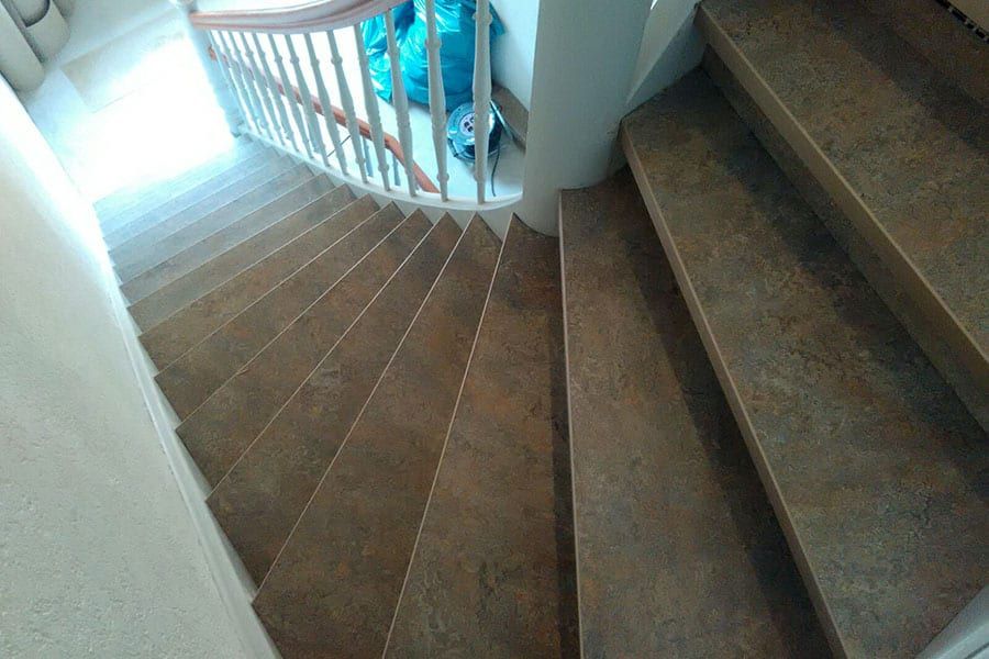 Treppenhausstufen mit Linoleum — Blick von oben auf die gewendelten Stufen und das Podest