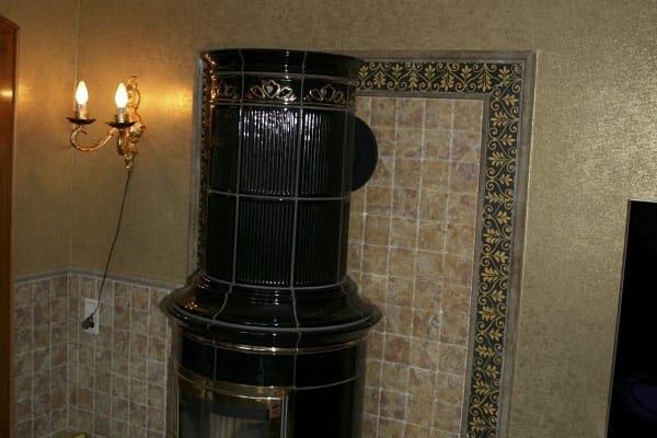 Wandfläche in goldener Struktur-Optik neben einem schwarzen Kachelofen